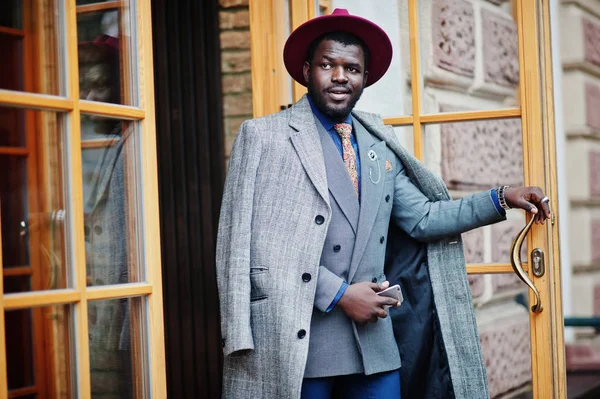 グレーのコート ジャケット ネクタイ カフェの入り口のドアに赤い帽子でスタイリッシュなアフリカ系アメリカ人モデル — ストック写真