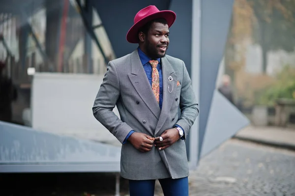 Stylish African American man model in gray jacket tie and red hat.
