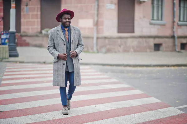 グレーのコート ジャケット ネクタイ 横断歩道の上を歩く赤い帽子でスタイリッシュなアフリカ系アメリカ人モデル — ストック写真