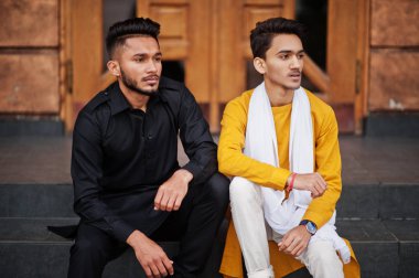 İki Hint şık arkadaş geleneksel giysiler içinde mans açık ve merdivenlerde oturan poz verdi.