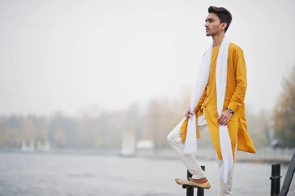 白いスカーフで黄色の伝統的な服でインドのスタイリッシュな男性ポーズに対して海の霧の桟橋が屋外 — ストック写真