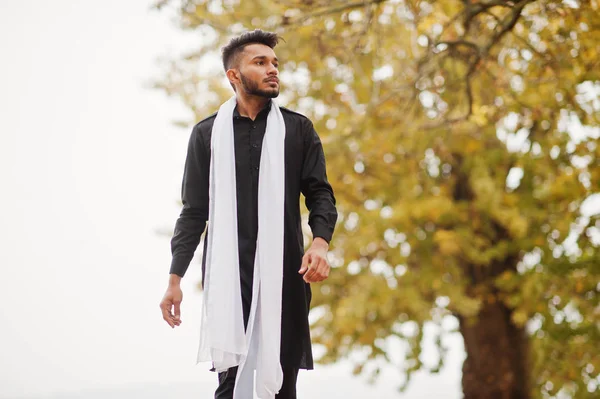 印度时尚男子在黑色的传统衣服与白色围巾摆在户外对秋叶树 — 图库照片