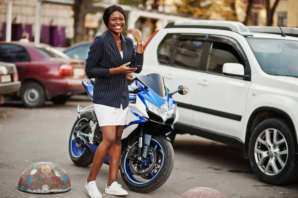 Success stylish african american woman with phone at hands against motorcycle.