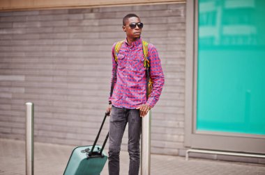 Afrika kökenli Amerikalı adam kareli gömlek, güneş gözlüğü ve kot çanta. Siyah adam traveler.