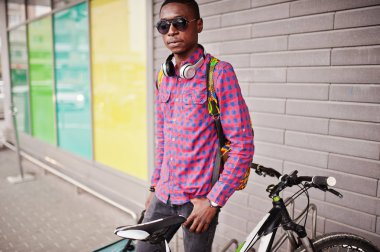 Kareli gömlek, güneş gözlüğü ve kot çanta ve sırt çantası bir Afrika kökenli Amerikalı adam. Siyah adam gezgin ile bisiklet. 