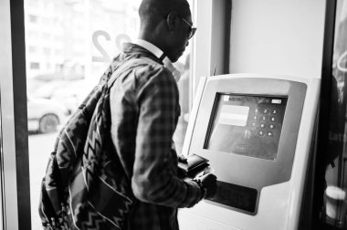 Afrika kökenli Amerikalı adam sırt çantası cüzdan el atm. siyah adam gezgin karşı holding ile kareli gömlekli.