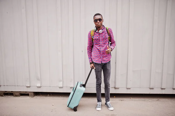 格子縞のシャツ サングラス スーツケースとバックパックのイヤホンでアフリカ系アメリカ人 壁に黒人男性旅行者 — ストック写真