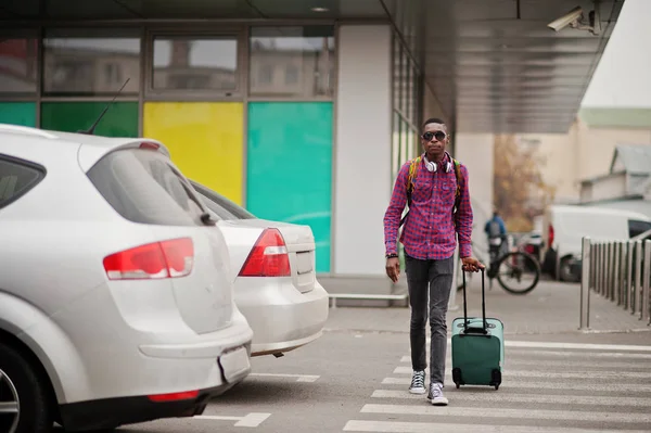 格子縞のシャツ サングラス スーツケースとバックパックのイヤホンでアフリカ系アメリカ人 横断歩道の上を歩く黒人旅行者 — ストック写真
