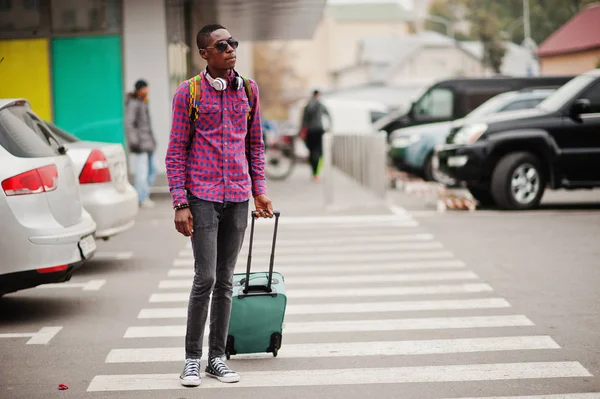 格子縞のシャツ サングラス スーツケースとバックパックのイヤホンでアフリカ系アメリカ人 横断歩道の上を歩く黒人旅行者 — ストック写真