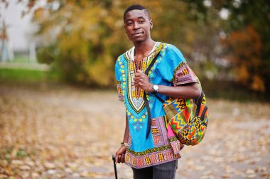 Sırt çantası ve bavul sonbahar park Afrika geleneksel forması Afrika adam. Göçmen gezgin.