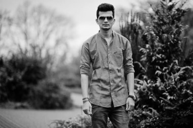 Kırmızı gömlek ve güneş gözlüğü Hintli adam açık poz verdi. Siyah ve beyaz fotoğraf.