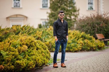 Siyah gömlek ve güneş gözlükleri şık Hintli açık poz verdi.