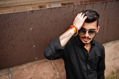 Siyah gömlek ve güneş gözlükleri şık Hintli açık poz verdi.