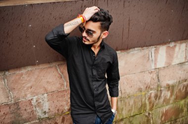 Siyah gömlek ve güneş gözlükleri şık Hintli açık poz verdi.