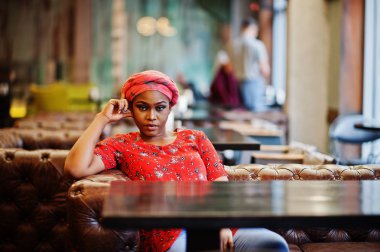 Kırmızı gömlek ve şapka şık Afrikalı kadın kapalı Cafe poz verdi..