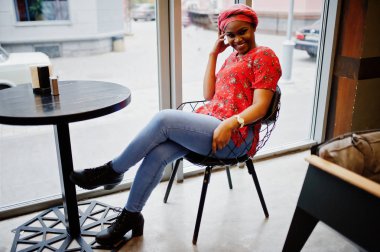 Kırmızı gömlek ve şapka şık Afrikalı kadın kapalı Cafe poz verdi..