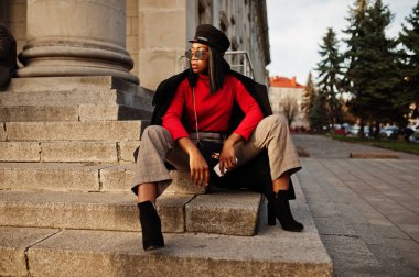 Afro-Amerikan moda kız ceket ve gazeteci çocuk şapkası, güneş gözlüğü Sokağı'nda poz verdi..