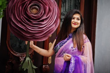 Geleneksel violet saree Hint hindu kıza Street yakınında büyük bir şekilde dekore edilmiş gül poz verdi.