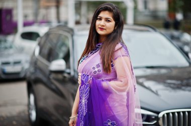 Geleneksel violet saree Hint hindu kıza Street siyah suv araba karşı poz verdi.