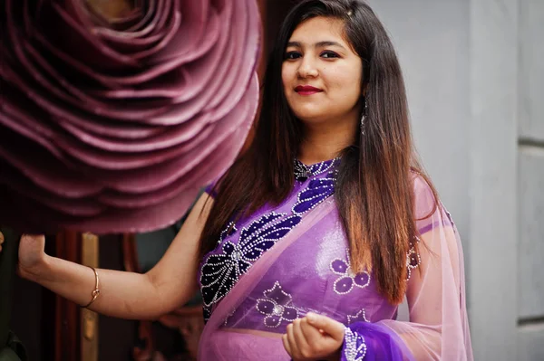 Geleneksel violet saree Hint hindu kıza Street yakınında büyük bir şekilde dekore edilmiş gül poz verdi.