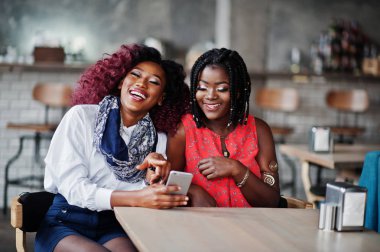 Café selfie telefonda yapma masada oturan çekici Afrikalı-Amerikalı iki kız arkadaş.