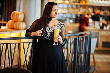 Portakal suyu el altında ile restoranda poz siyah sari giysili güzel Hintli kız.