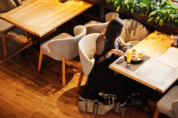 Restoranda, suyu ve salata ile masada oturan siyah sari giysili güzel Hintli kız oluşturuyordu. Cep telefonu arıyorum.