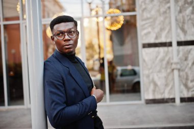 İnanılmaz Afro-Amerikan erkek giyimi mavi ceket broş ile seyir, siyah boğazlı kazak ve gözlük Sokağı'nda poz verdi. Şık siyah adam.