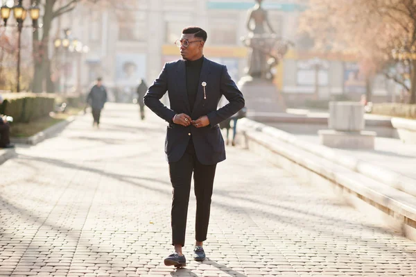 İnanılmaz Afro-Amerikan erkek giyimi mavi ceket broş ile seyir, siyah boğazlı kazak ve gözlük Sokağı'nda poz verdi. Şık siyah adam.