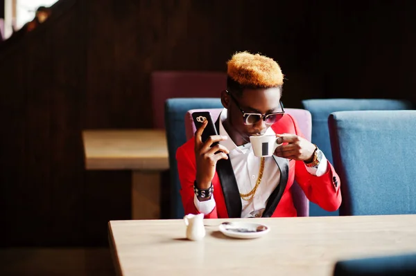 ハイライト髪とサングラス カフェでコーヒーを飲みながら座っていると 携帯電話で話す 赤いスーツでアフリカ系アメリカ人のファッションモデル — ストック写真