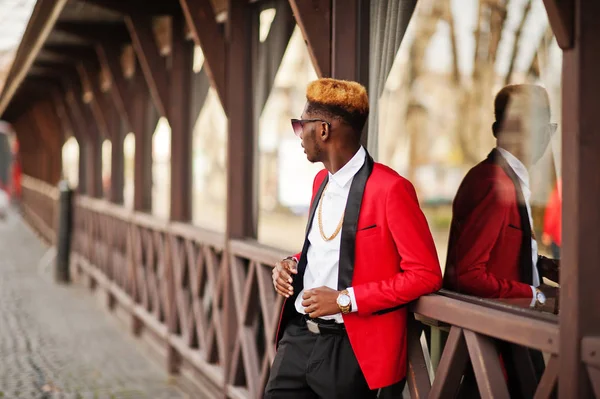 Fashion african american man model at red suit, with highlights hair posed at street.