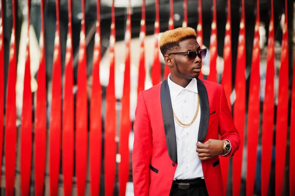 Fashion african american man model at red suit, with highlights hair posed at street.