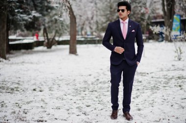 Zarif Hint maço erkek model üzerinde takım elbise ve kravat pembe, kış gününde poz güneş gözlüğü.