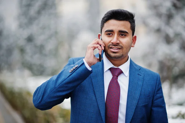 Elegant indian fashionable man model on suit posed at winter day and speaking on phone.