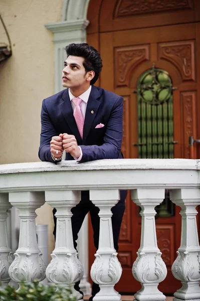 优雅的印度大男子模型西装和粉红色的领带靠在栏杆上 — 图库照片