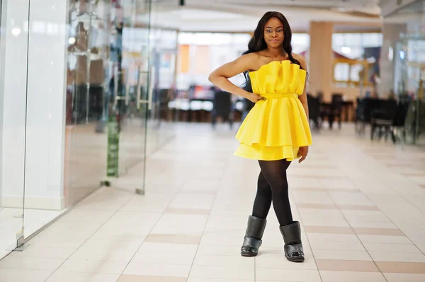 Stylish african american woman at yellow dreess posed at mall.