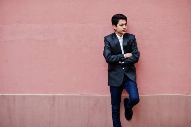 Takım elbise genç Hintli adam pembe duvara poz verdi..