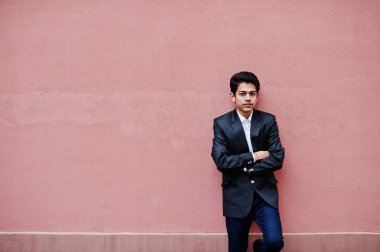 Takım elbise genç Hintli adam pembe duvara poz verdi..