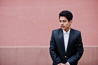 Takım elbise genç Hintli adam pembe duvara poz verdi..