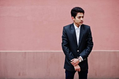 Takım elbise genç Hintli adam pembe duvara poz verdi..