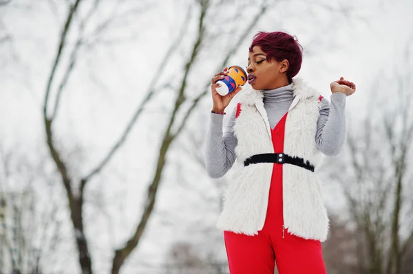 African american woman in red pants and white fur coat jacket