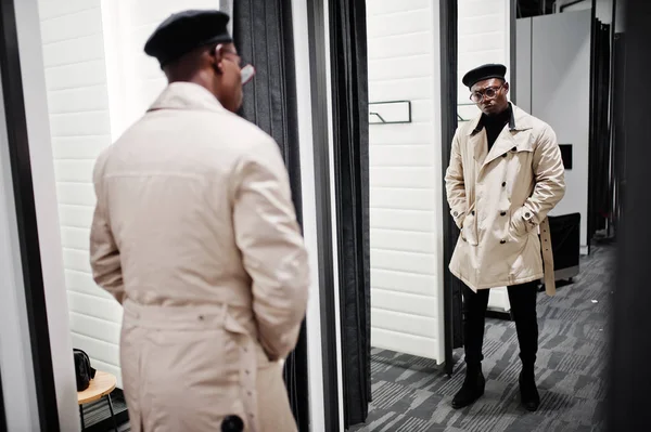 スタイリッシュなカジュアルなアフリカ系アメリカ人黒いベレー帽とフィッティング ルーム服店で白いトレンチ レインコートで鏡を見て — ストック写真