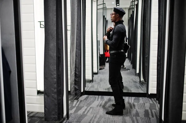 スタイリッシュなカジュアルなアフリカ系アメリカ人黒い服とベレー帽でフィッティング ルーム服店でウエスト バッグに鏡を見て — ストック写真