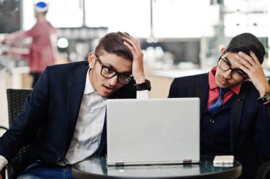 Ofiste kafe üzerinde oturan ve laptop arıyorum takım elbiseli iki Hint iş adamı. Hayal kırıklığına uğramış surat.