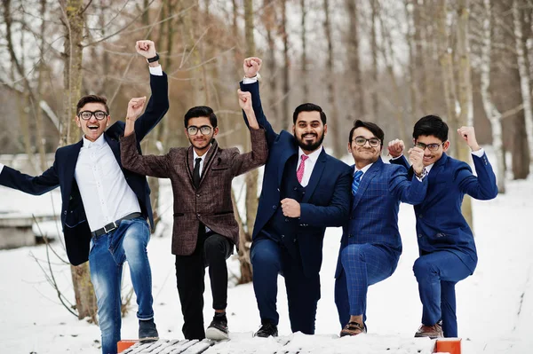 Group of five indian businessman in suits posed outdoor in winter day at Europe, hands up and show happy emotions.