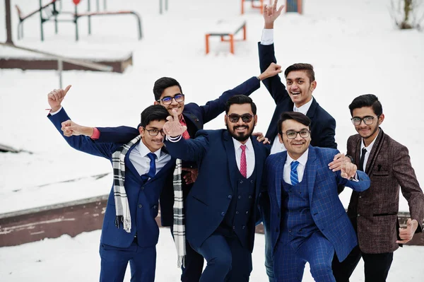 Group of six indian businessman in suits posed outdoor in winter day at Europe, hugs and happy emotions.