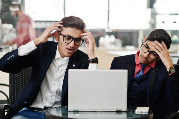 Ofiste kafe üzerinde oturan ve laptop arıyorum takım elbiseli iki Hint iş adamı. Hayal kırıklığına uğramış surat.