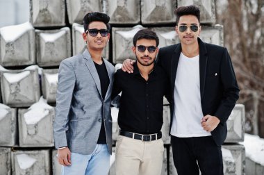 Taş bloklar karşı yöneltilen güneş gözlüğü üç sıradan genç Hint grup mans.