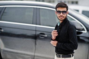 Siyah gömlek ve güneş gözlüğü rahat Hint delikanlı suv araba karşı poz verdi..
