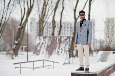 Casual Genç Hintli gümüş ceket ve güneş gözlüğü kış gününde poz verdi..